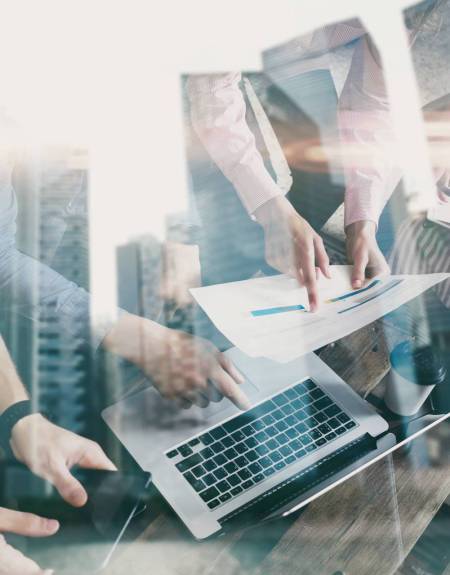 Double exposure of young coworkers working together on new startup project in modern office.Business people brainstorming concept.Skyscraper building on the blurred background.Vertical,flare effect